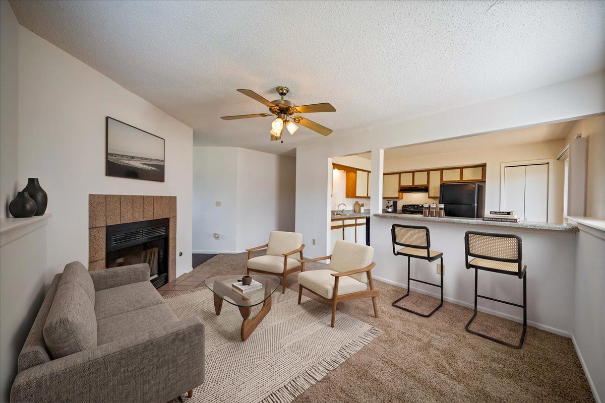Open-concept living room featuring a fireplace, breakfast bar seating, and adjacent kitchen.